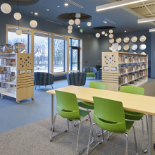 chairs, shelves with books, lighting, and big windows in the teen area
